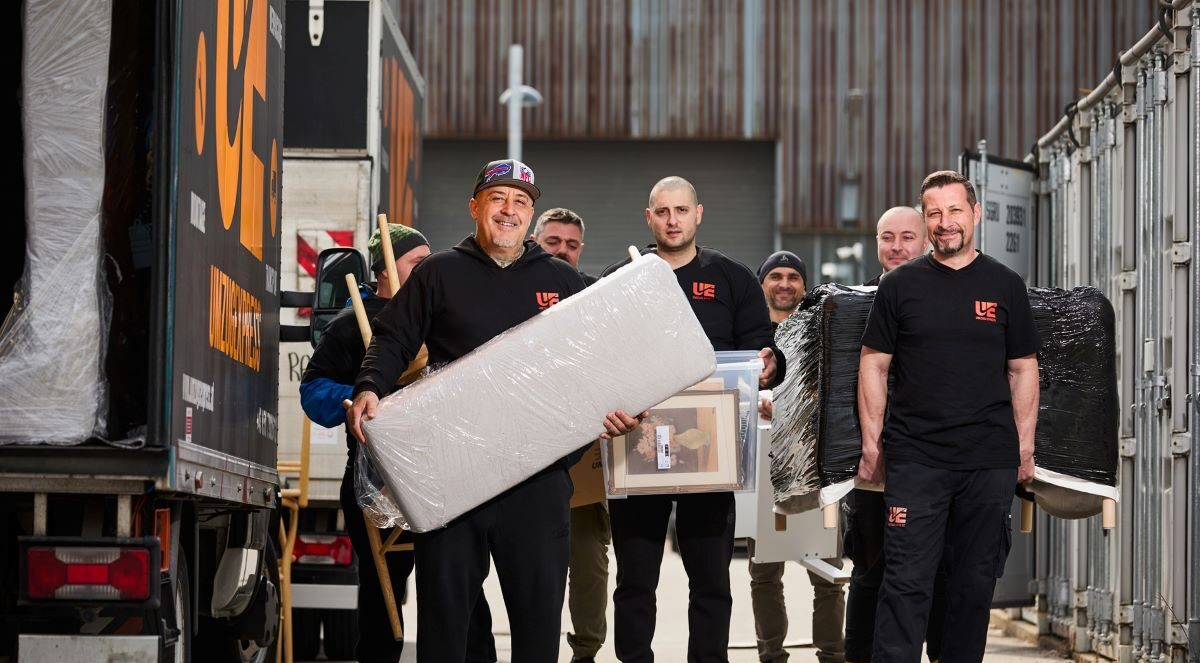 Team von Umzugsexpress transportiert große Möbelstücke und Kartons bei einem professionellen Firmenumzug in Wien